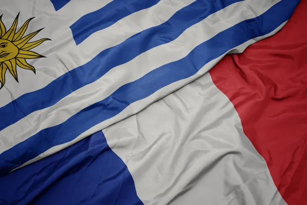Размахивая красочным флагом Франции и национальным флагом Уругвая . — стоковое фото