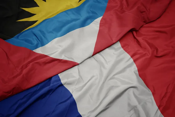 Falujące kolorowe flagi Francji i flagi narodowej Antigua i Barbuda. — Zdjęcie stockowe
