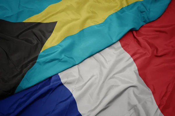 Schwenken bunte Fahne von Frankreich und Nationalflagge von Bahamas. — Stockfoto