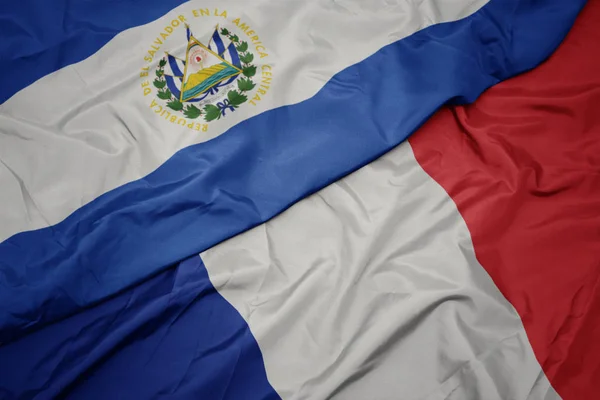 Размахивая красочным флагом Франции и национальным флагом Сальвадора . — стоковое фото