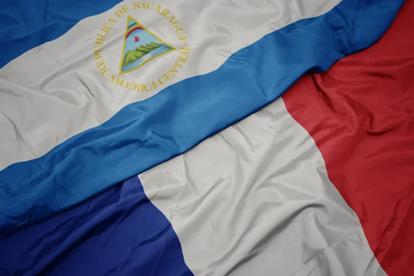 Ondeando colorida bandera de francia y bandera nacional de nicaragua . — Foto de Stock