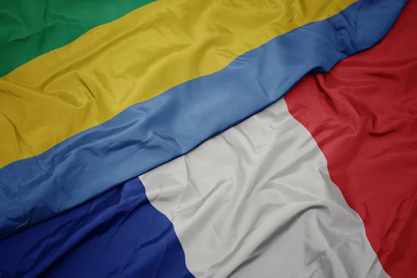 Ondeando colorida bandera de Francia y bandera nacional de Gabón . — Foto de Stock
