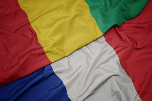 Falujące kolorowe flagi Francji i Narodowej flagi Gwinei. — Zdjęcie stockowe