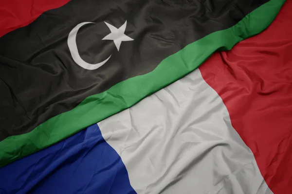 Ondeando colorida bandera de francia y bandera nacional de libya . — Foto de Stock