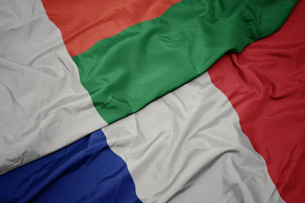 Schwenken bunte Fahne von Frankreich und Nationalflagge von Madagaskar. — Stockfoto