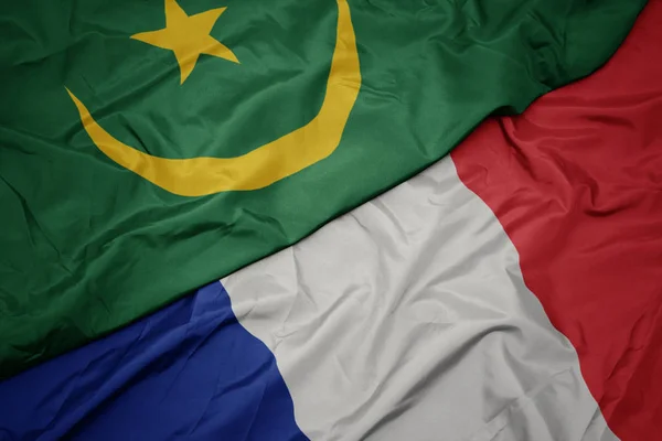 Mávající barvitá vlajka Francie a národní vlajka Mauritánie. — Stock fotografie