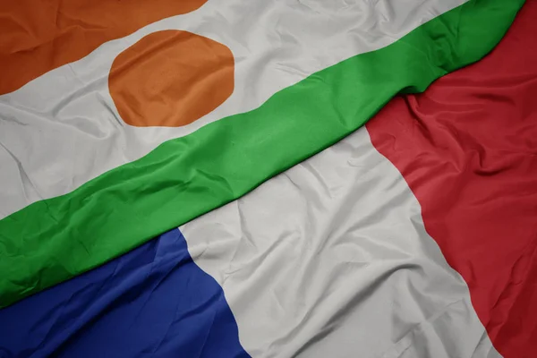 Agitant drapeau coloré de la france et drapeau national du niger . — Photo