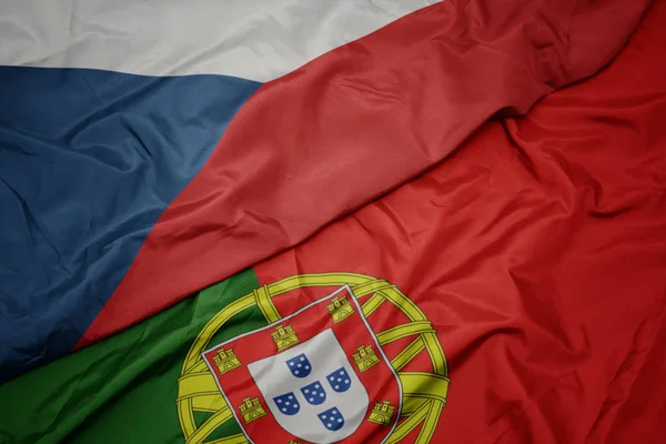 waving colorful flag of portugal and national flag of czech republic.