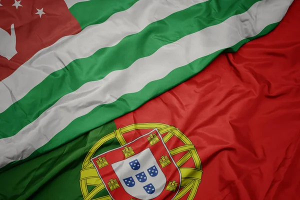 Mávat barevnou vlajku Portugalska a národní vlajka Abcházie. — Stock fotografie