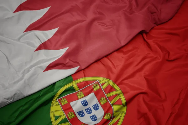 waving colorful flag of portugal and national flag of bahrain.