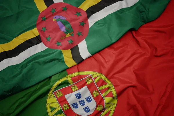 Mávající barevná vlajka Portugalska a národní vlajka Dominiky. — Stock fotografie