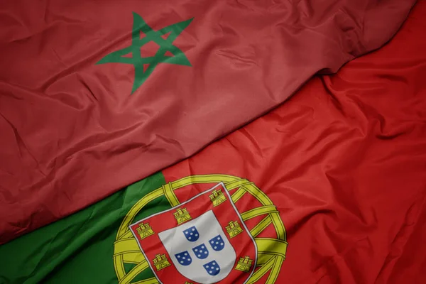 Zwaaiende kleurrijke vlag van Portugal en de nationale vlag van Marokko. — Stockfoto