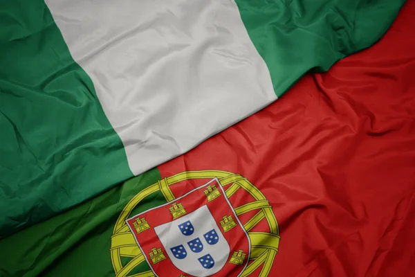 Agitant drapeau coloré du drapeau portugais et national du Nigéria . — Photo