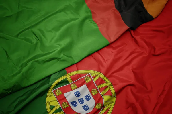 Falujące kolorowe flagi Portugalii i flagi narodowej Zambii. — Zdjęcie stockowe