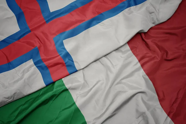 Schwenken bunte Flagge Italiens und Nationalflagge der Färöer-Inseln. — Stockfoto