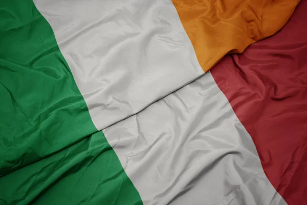 Agitant drapeau coloré de l'Italie et drapeau national de l'Irlande . — Photo