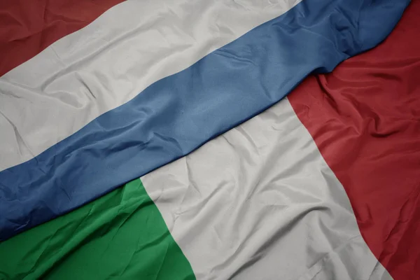 Mávající barvitá vlajka Itálie a státní vlajka Lucemburska. — Stock fotografie