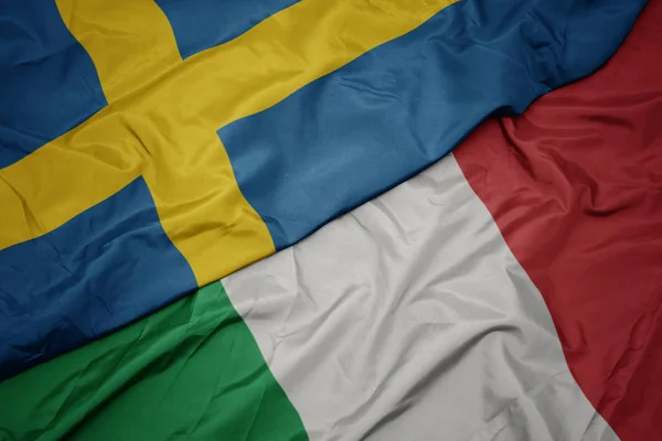 Sventolando bandiera colorata d'Italia e bandiera nazionale di Svezia . — Foto Stock
