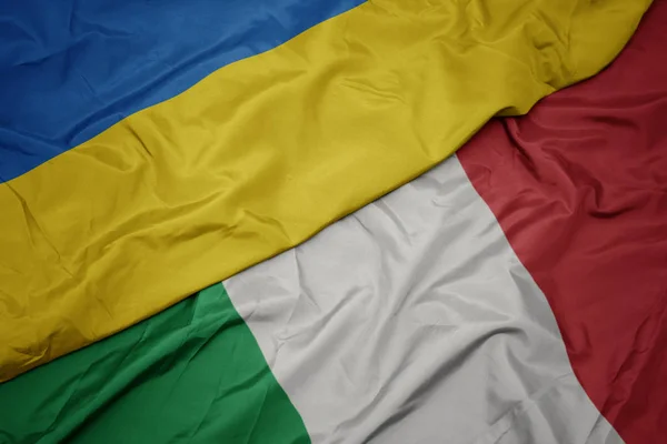 Ondeando colorida bandera de italia y bandera nacional de Ucrania . — Foto de Stock