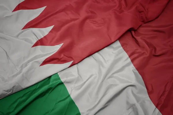 waving colorful flag of italy and national flag of bahrain.