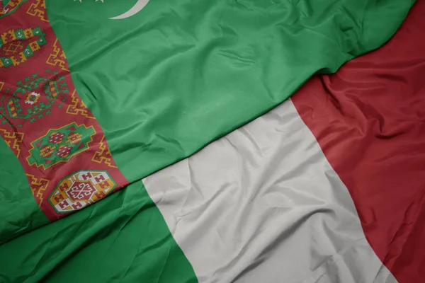 Sventolando bandiera colorata d'Italia e bandiera nazionale del turkmenistan . — Foto Stock