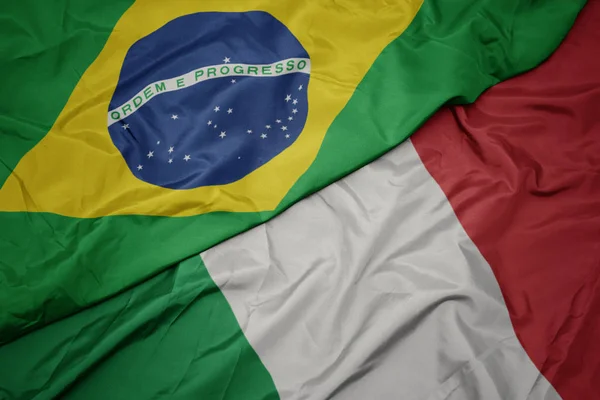 Ondeando colorida bandera de italia y bandera nacional de Brasil . — Foto de Stock