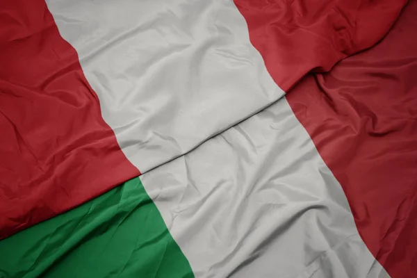 Zwaaiende kleurrijke vlag van Italië en de nationale vlag van Peru. — Stockfoto