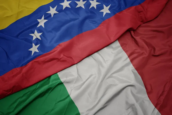 Ondeando colorida bandera de italia y bandera nacional de venezuela . — Foto de Stock