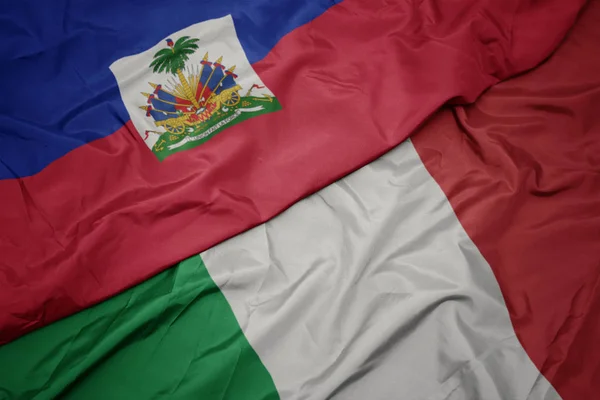 Zwaaiende kleurrijke vlag van Italië en de nationale vlag van Haïti. — Stockfoto