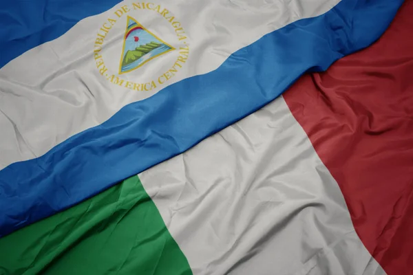 Ondeando colorida bandera de italia y bandera nacional de nicaragua . —  Fotos de Stock