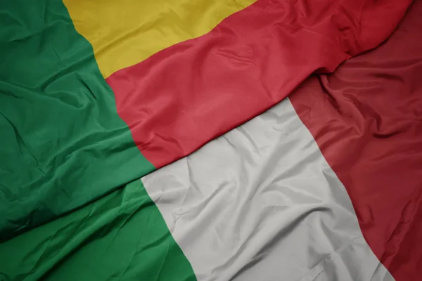 Ondeando colorida bandera de italia y bandera nacional de benin . — Foto de Stock