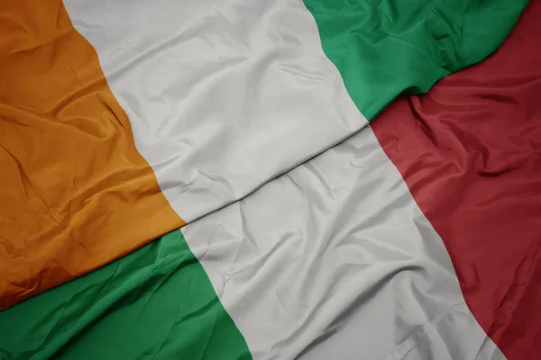 Agitant le drapeau coloré de l'Italie et le drapeau national de cote divoire . — Photo