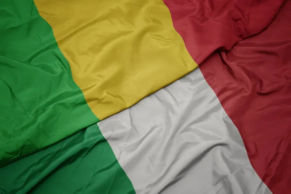 Falujące kolorowe flagi Włoch i flagi narodowej Mali. — Zdjęcie stockowe