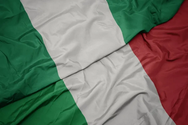 Sventolando bandiera colorata d'Italia e bandiera nazionale della Nigeria . — Foto Stock