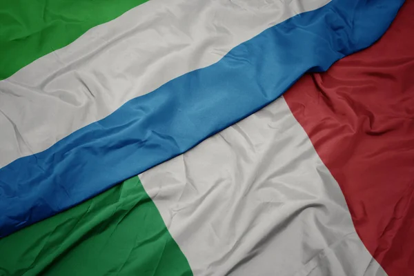Размахивая красочным флагом Италии и национальным флагом Сьерра-Леоне . — стоковое фото