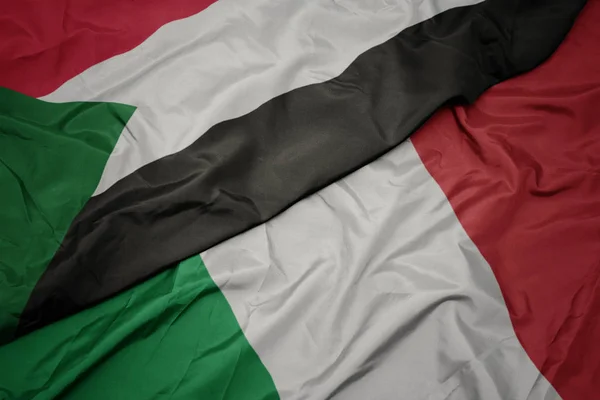 Waving colorful flag of italy and national flag of sudan. — Stock Photo, Image