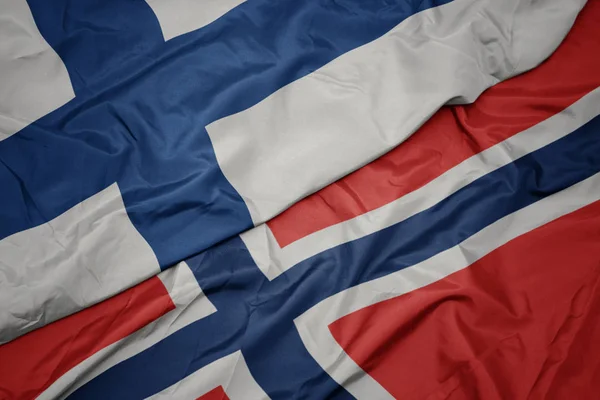 Zwaaiende kleurrijke vlag van Noorwegen en de nationale vlag van Finland. — Stockfoto