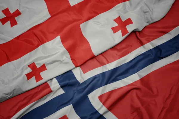 Zwaaiende kleurrijke vlag van Noorwegen en de nationale vlag van Georgië. — Stockfoto