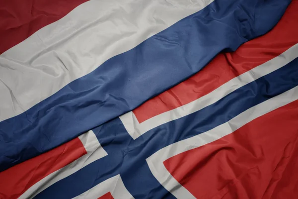 Schwenken bunte Flagge Norwegens und Nationalflagge der Niederlande. — Stockfoto