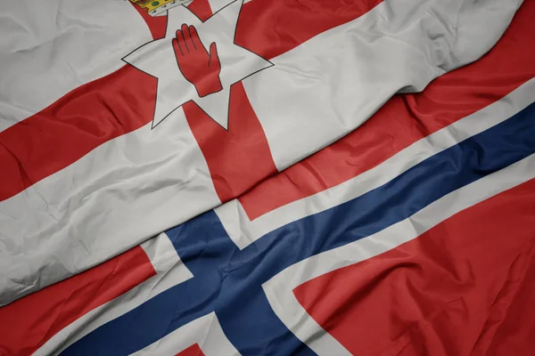 Schwenken bunte Flagge von Norwegen und Nationalflagge von Nordirland. — Stockfoto