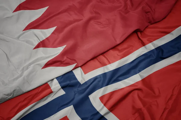 waving colorful flag of norway and national flag of bahrain.