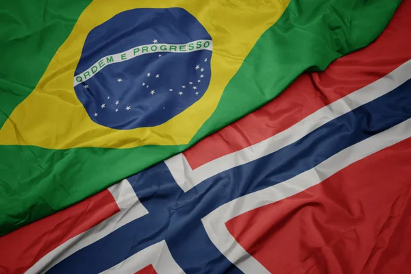 Acenando bandeira colorida de norway e bandeira nacional do brasil . — Fotografia de Stock