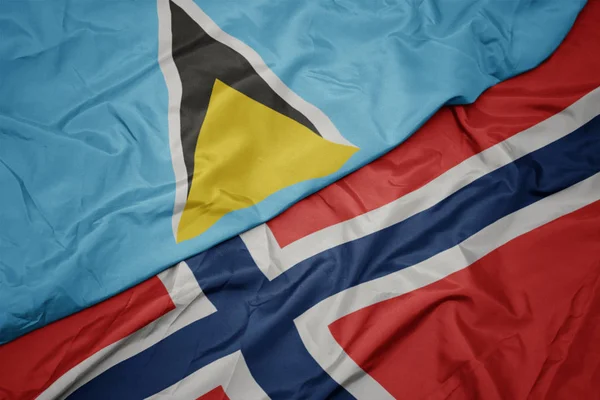 Mávající barevná vlajka Norska a národní vlajka svaté Lucie. — Stock fotografie
