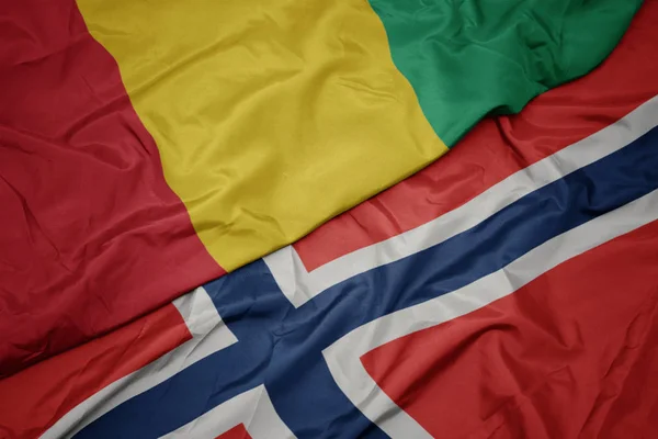 Falujące kolorowy flaga Norwegii i flagi narodowej Gwinei. — Zdjęcie stockowe