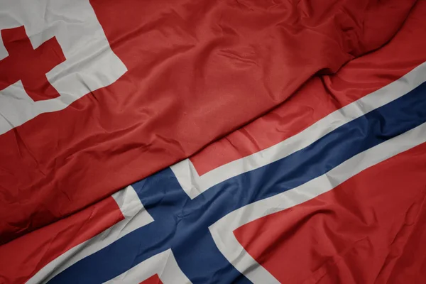 Zwaaiende kleurrijke vlag van Noorwegen en de nationale vlag van Tonga , . — Stockfoto