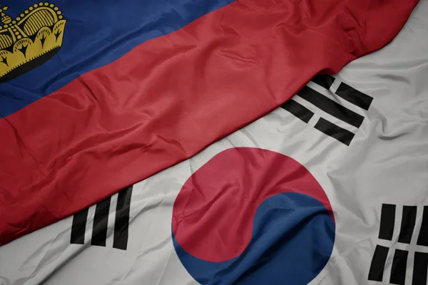 Zwaaiende kleurrijke vlag van Zuid-Korea en de nationale vlag van Liechtenstein. — Stockfoto