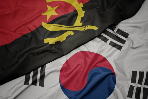 Ondeando colorida bandera de Corea del Sur y bandera nacional de Angola . — Foto de Stock