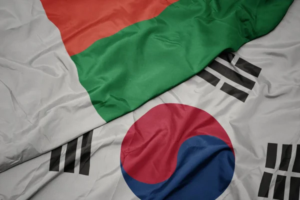 Ondeando colorida bandera de Corea del Sur y bandera nacional de madagascar . — Foto de Stock