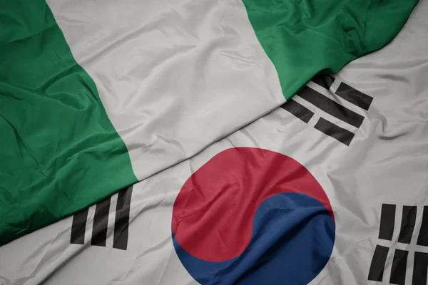 Ondeando colorida bandera de Corea del Sur y bandera nacional de nigeria . — Foto de Stock