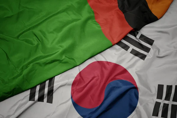 Ondeando colorida bandera de Corea del Sur y bandera nacional de zambia . — Foto de Stock